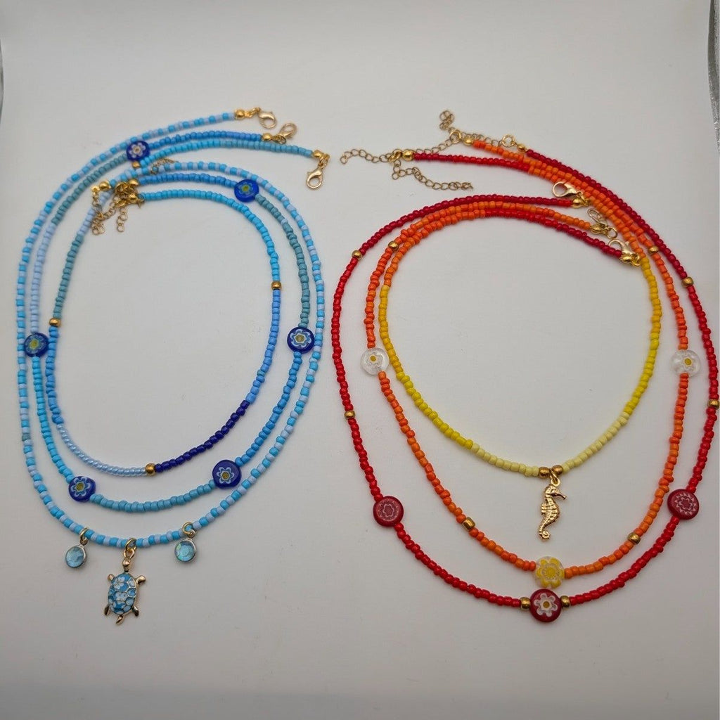 3-piece glass beaded necklace set laid out: blue and red strands with turtle and seahorse
