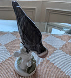 Porcelain woodpecker figurine with dark plumage and white flowers on round base, side view