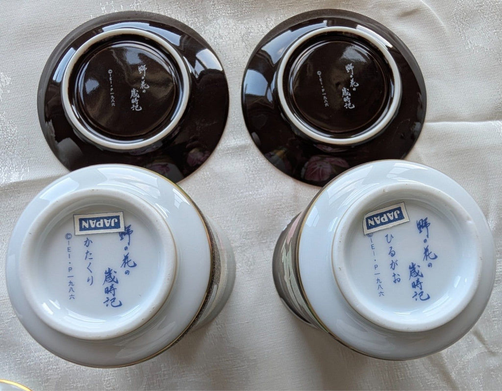 Two yunomi cup bases and saucers, glossy dark glaze with blue maker marks.
