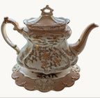 Cream and gold Rococo porcelain teapot with floral scrollwork and curved spout