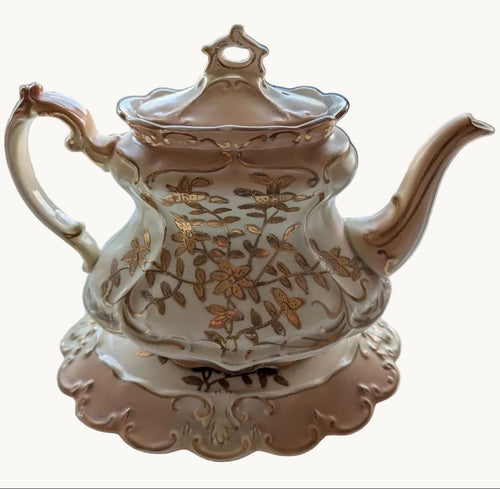Cream and gold Rococo porcelain teapot with floral scrollwork and curved spout
