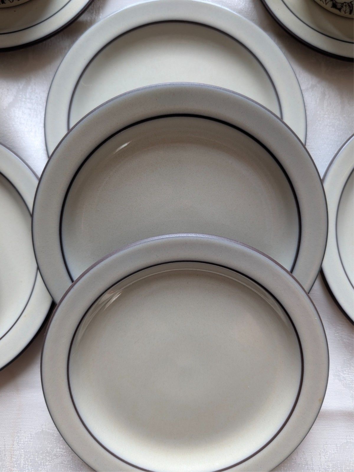 Stoneware plates with bordered rims and floral center, cream with blue-black design