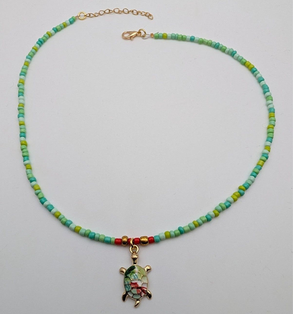 Green beaded sea turtle choker necklace with small gold-tone turtle pendant and clasp