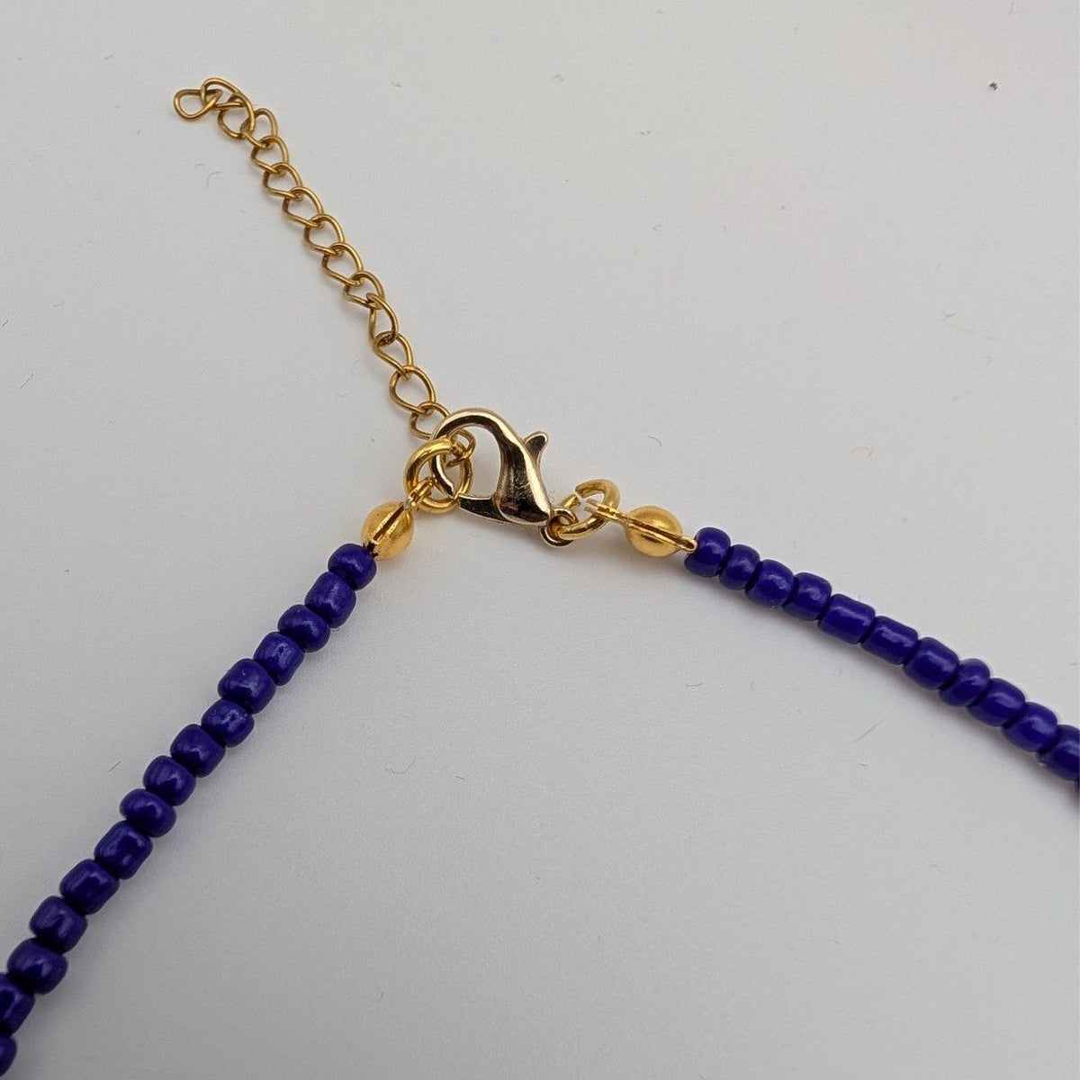 Gold chain clasp end of a blue glass beaded choker