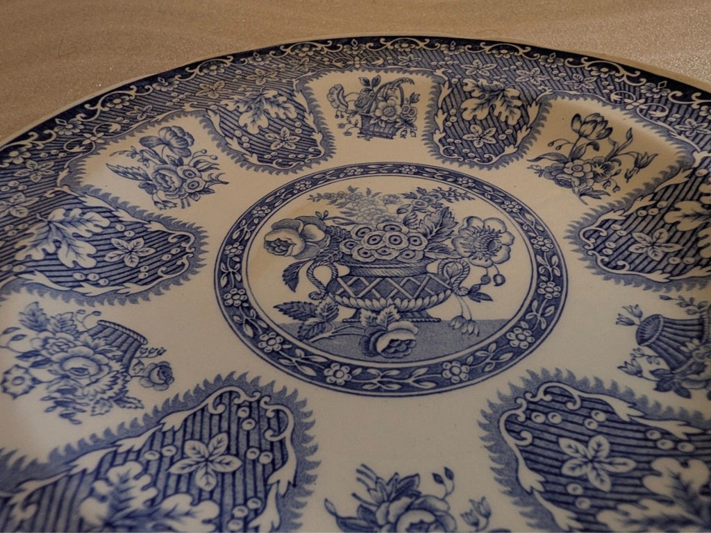 Round blue-and-white dinner plate with floral filigree border and central medallion