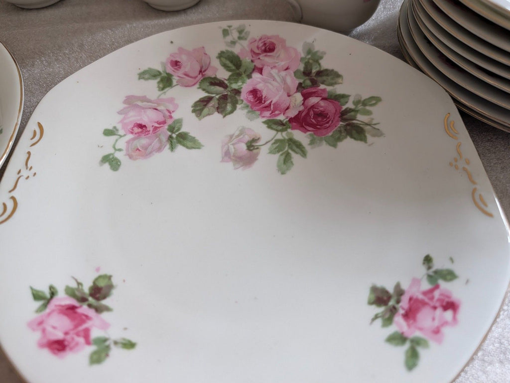 Porcelain dinner plate with pink roses and green leaves, gold scroll corner accents