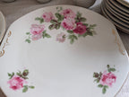 Porcelain dinner plate with pink roses and green leaves, gold scroll corner accents