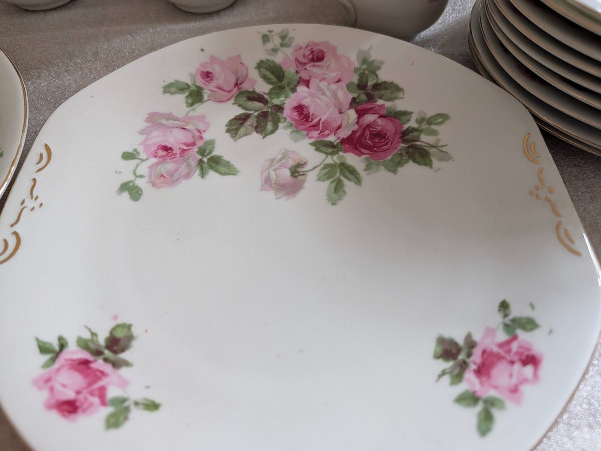 Porcelain dinner plate with pink roses and green leaves, gold scroll corner accents