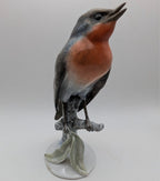 Hand-painted porcelain robin bird figurine with orange chest and gray body, standing on base