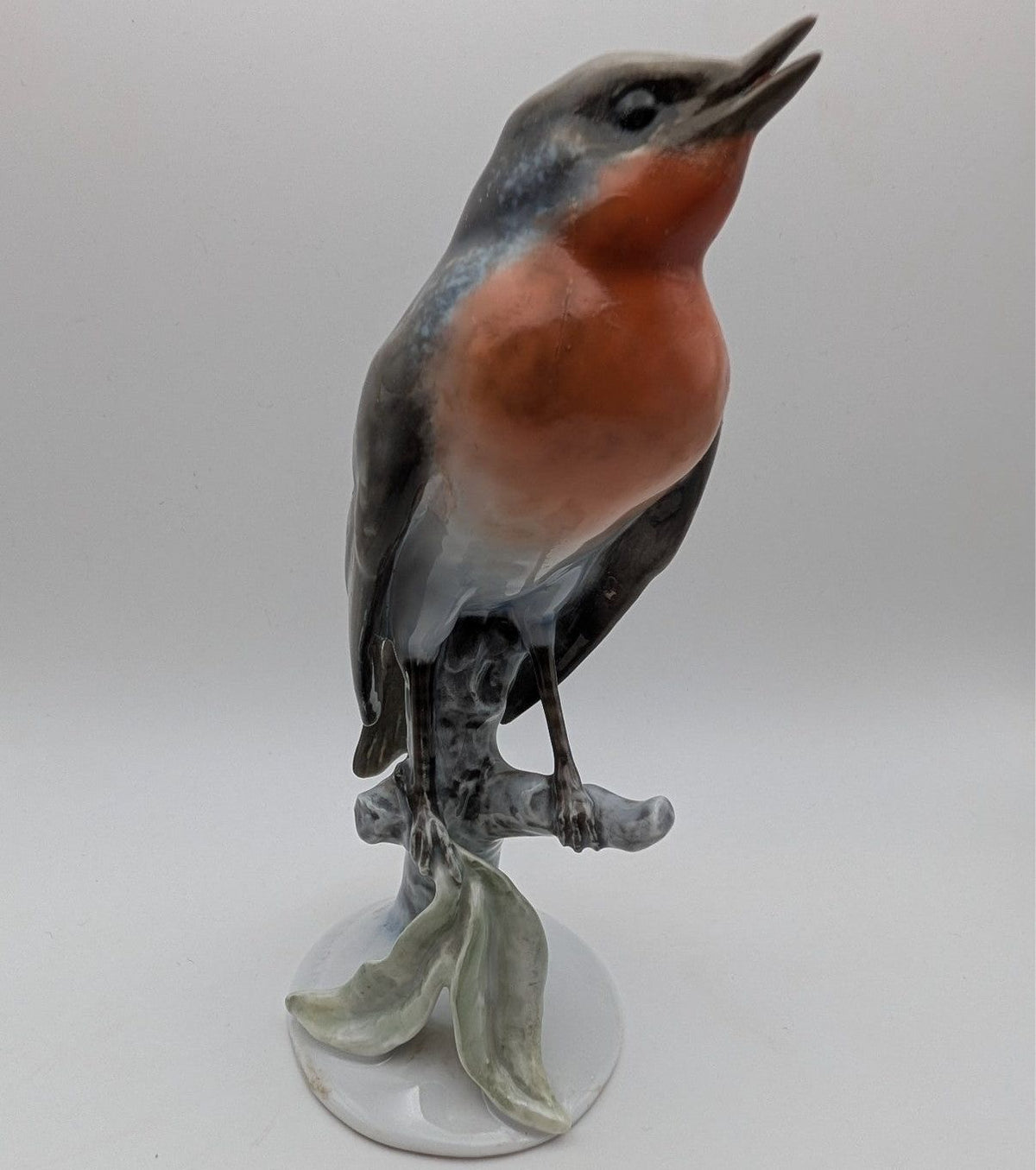 Hand-painted porcelain robin bird figurine with orange chest and gray body, standing on base