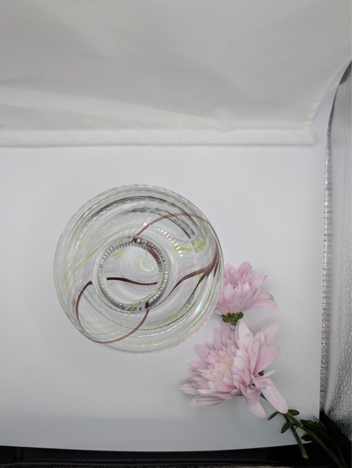 Clear glass bud vase with internal swirl and pink blossoms, side angle
