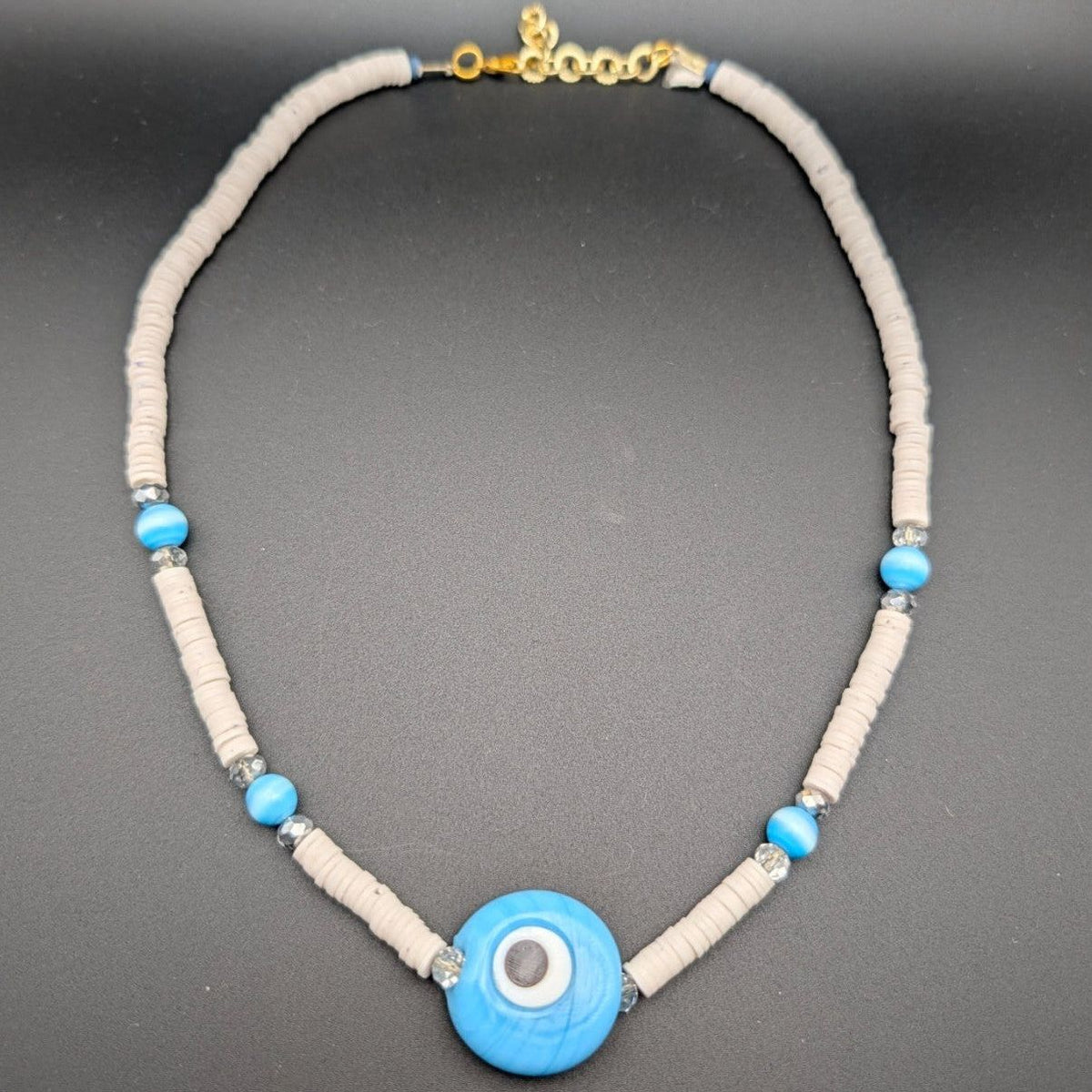 Cream heishi bead choker with blue evil-eye pendant and small spacer beads