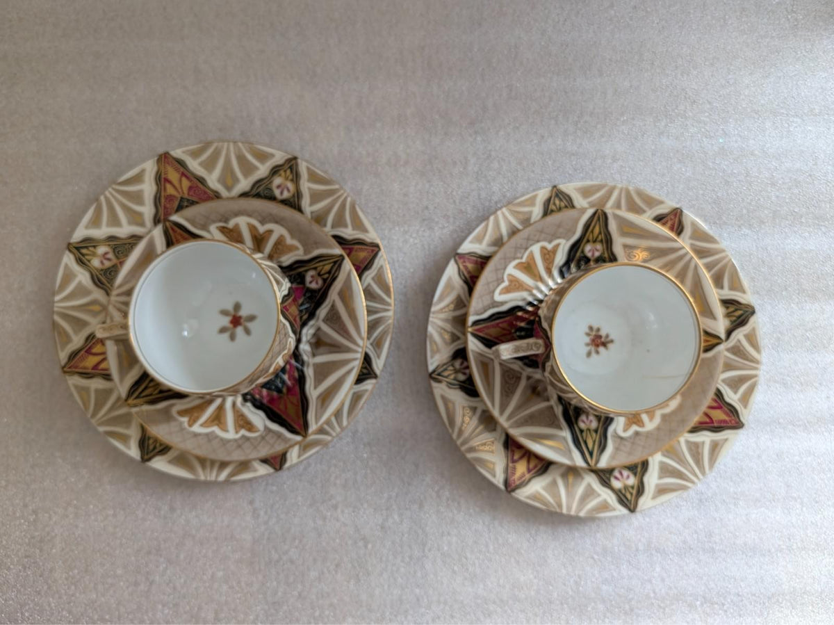 Porcelain cups and saucers, top view, ornate geometric border and floral accents
