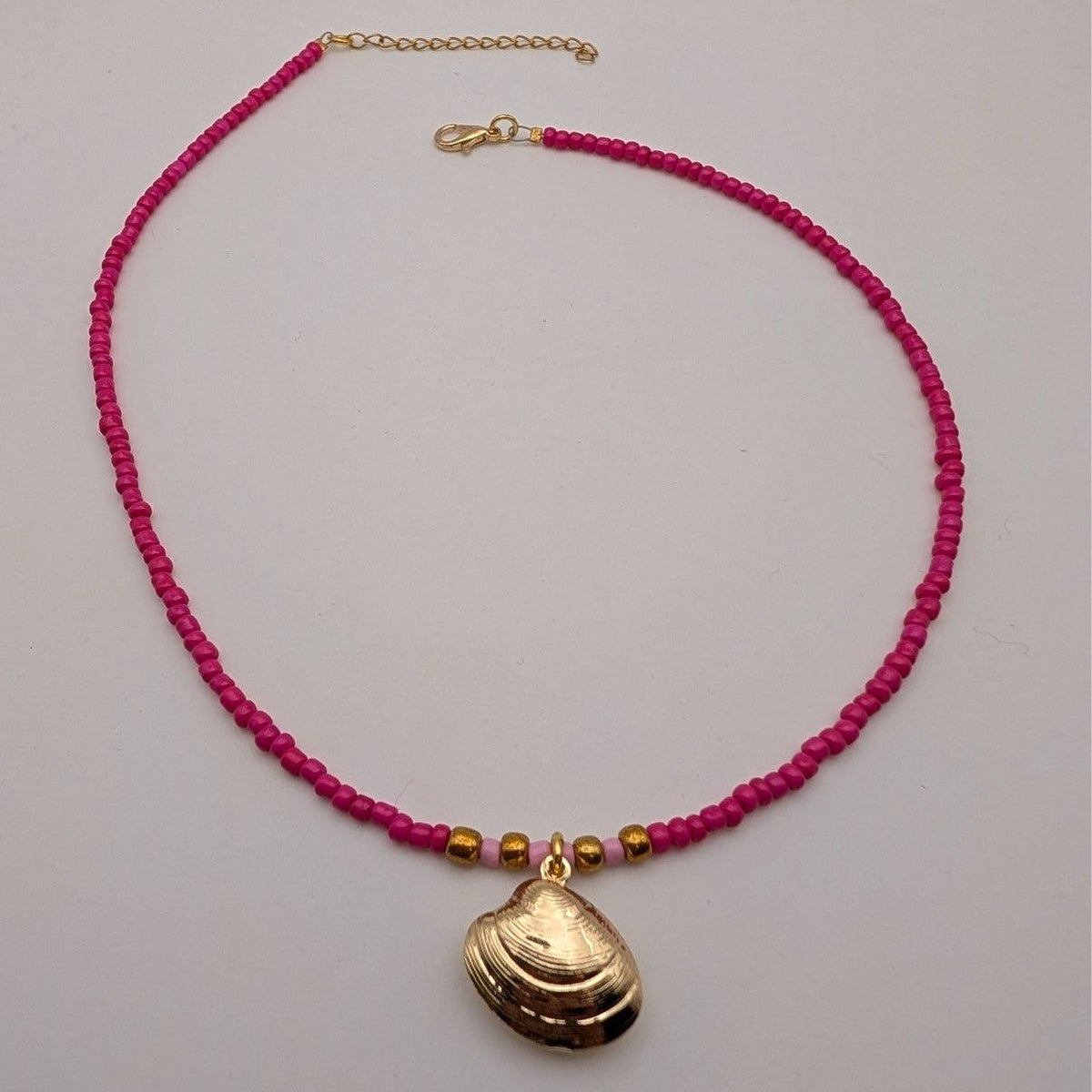 Pink beaded choker necklace with large seashell pendant and small gold beads