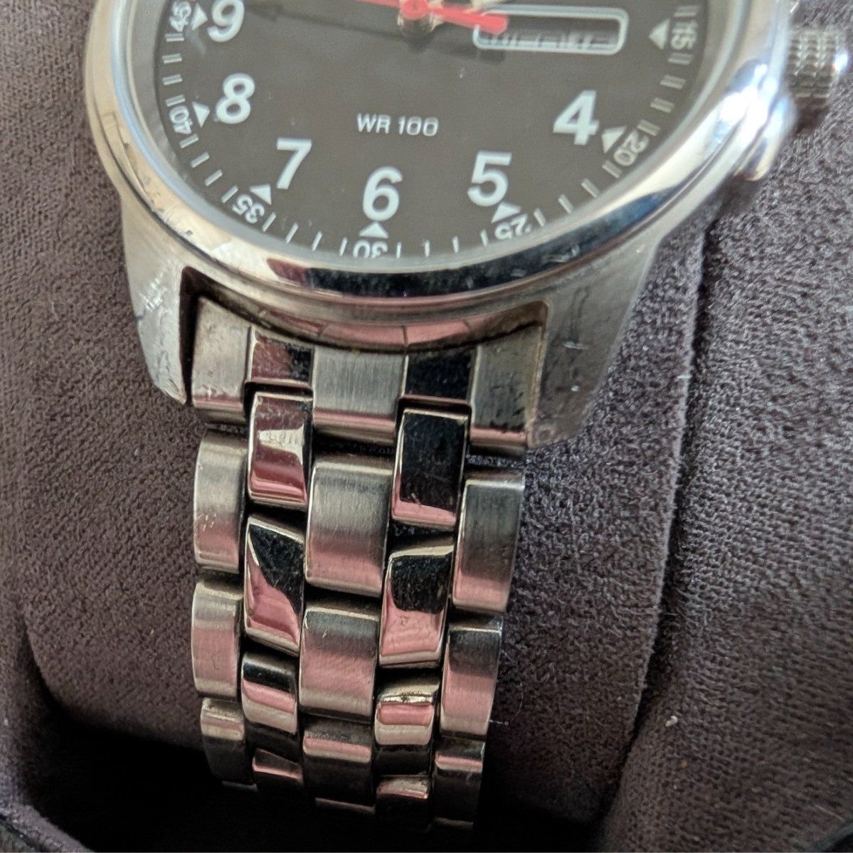 Military style watch close-up, black dial and shiny steel bracelet links