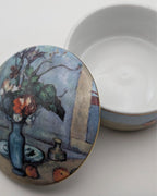 Porcelain trinket box lid with painted blue vase scene, open to show base