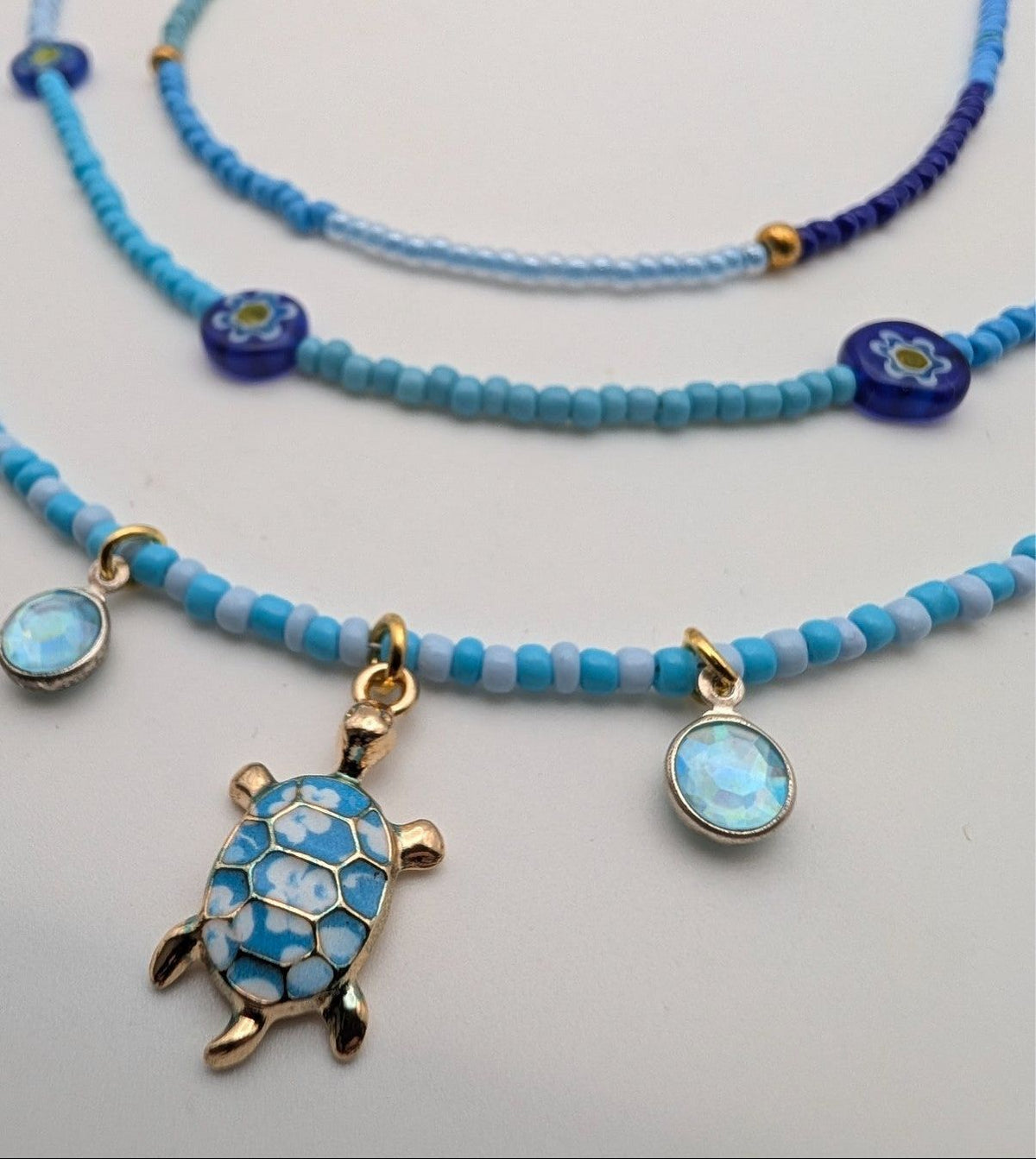 Blue glass beaded necklace set with layered sea turtle charm and round opal-like beads