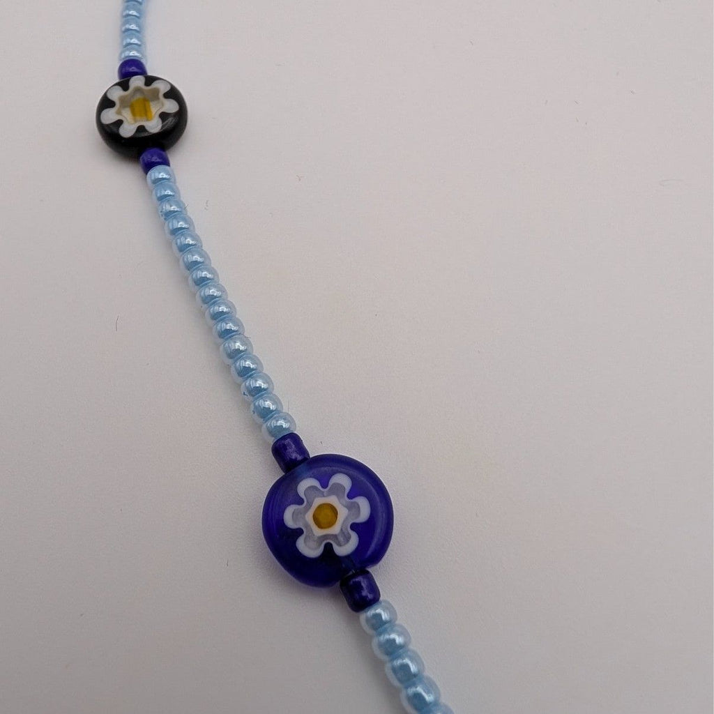 Light blue beaded necklace with blue flower disc charm and dark blue beads