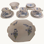 Bone china tea set pieces with blue forget-me-not floral pattern and gold trim