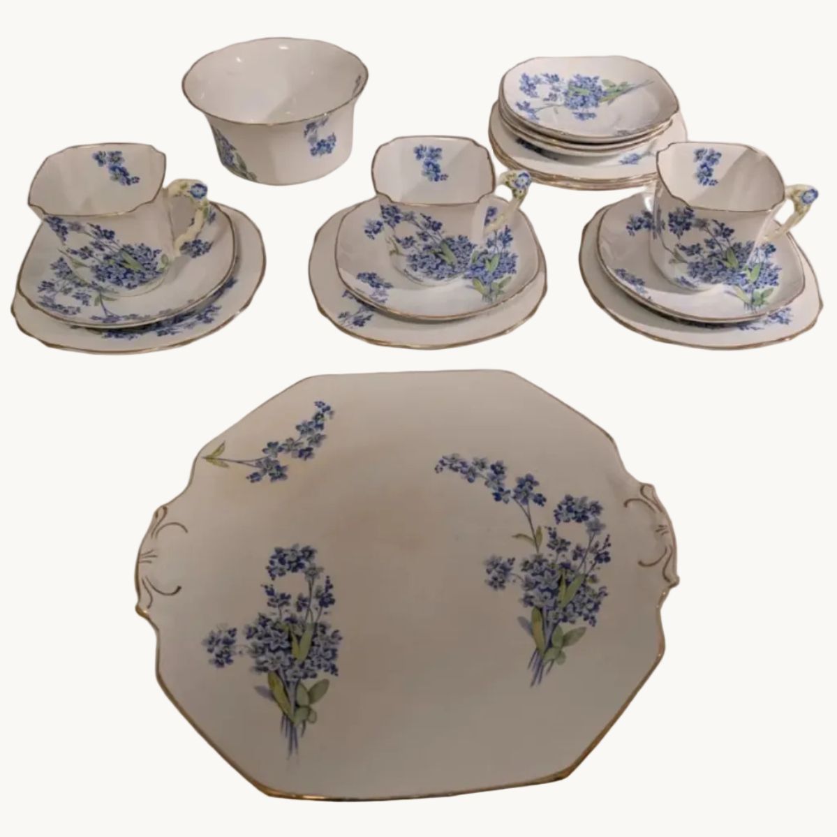 Bone china tea set pieces with blue forget-me-not floral pattern and gold trim