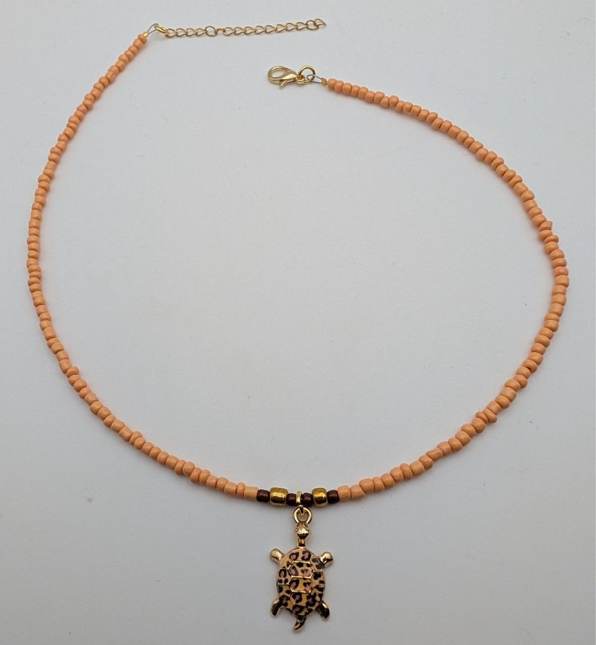 Peach beaded sea turtle choker necklace with gold-tone turtle pendant and clasp