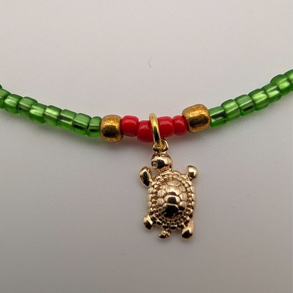 Green glass beaded choker with red beads and gold turtle charm pendant