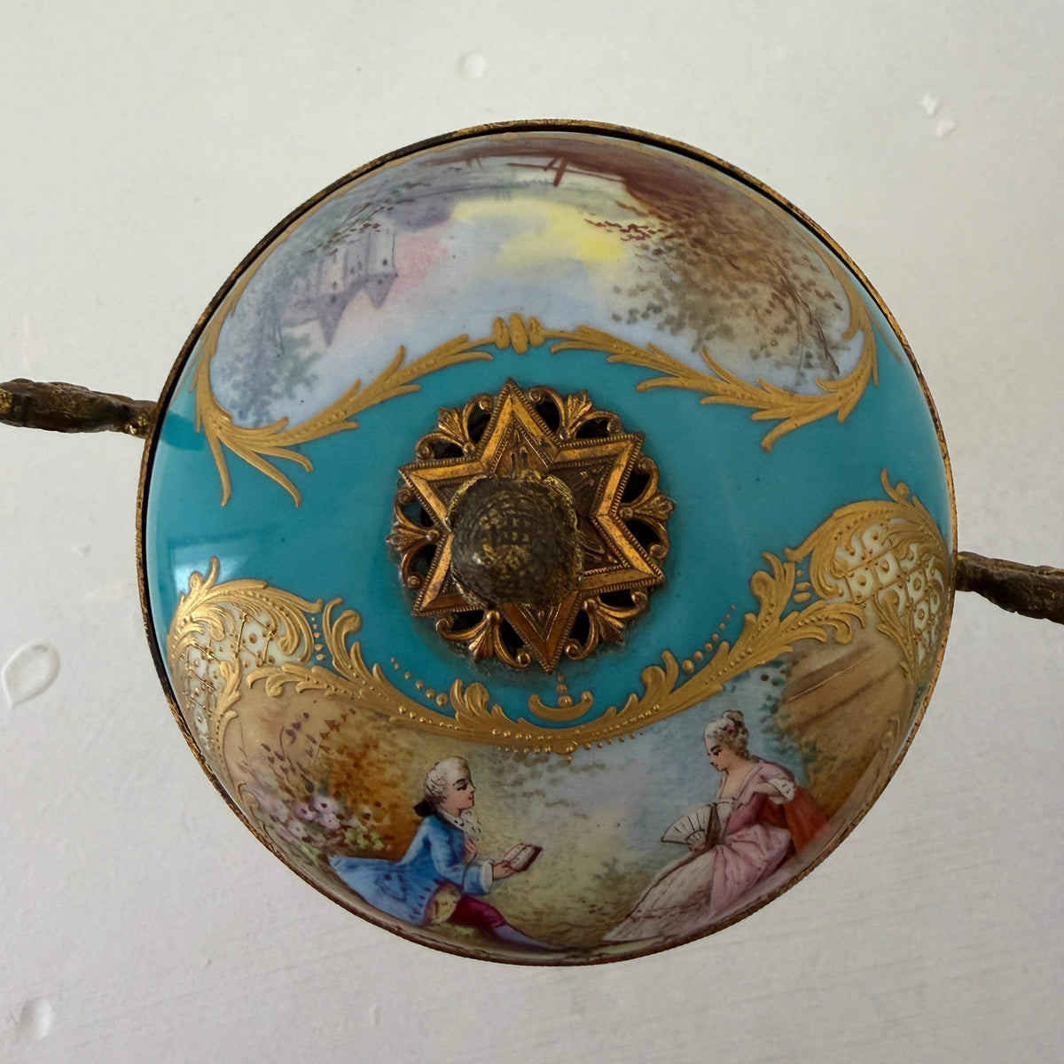 Blue porcelain lid top with painted figures and ornate central gilt medallion