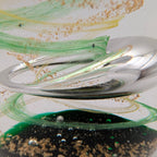 Close-up of teardrop glass paperweight with green-and-gold spiral swirl