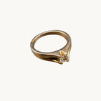 Gold tone solitaire costume ring with clear faceted rhinestone and sculpted band detail