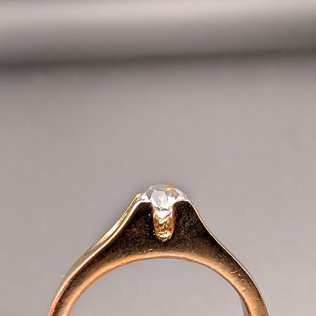Clear faceted rhinestone solitaire setting on a gold tone costume ring band