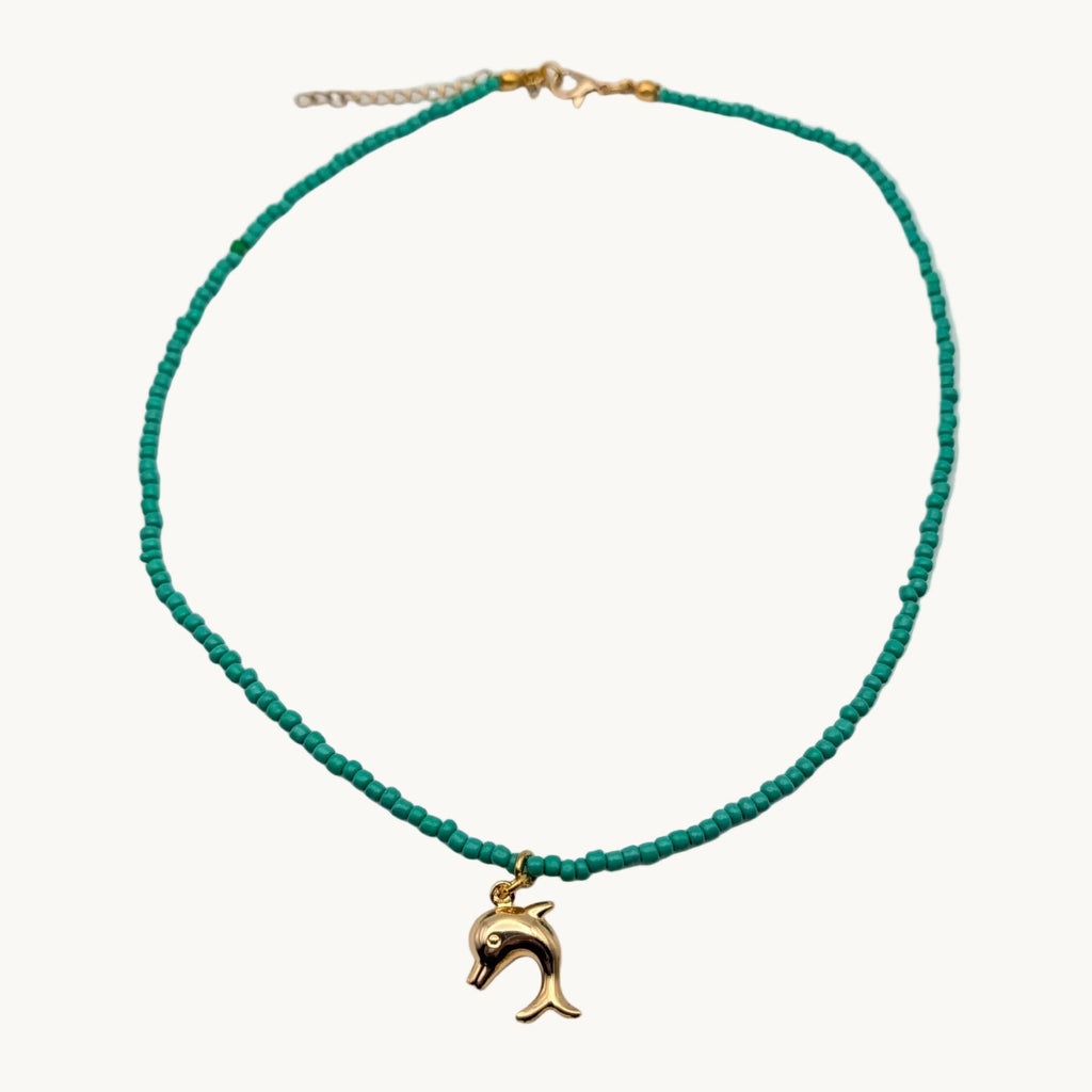 A delicate beaded necklace featuring vibrant turquoise green beads and a small gold-tone dolphin pendant.