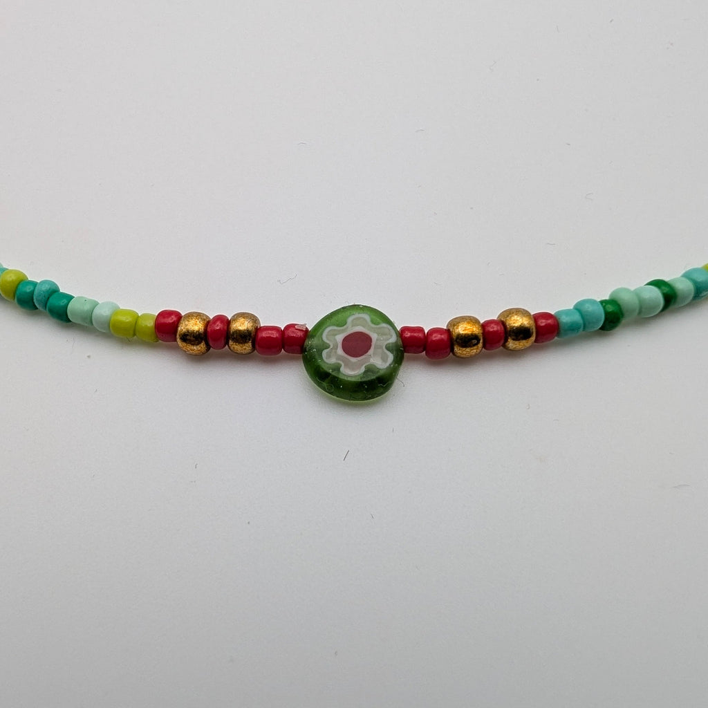 Close-up of green millefiori flower bead and gold-tone accents on multicolour choker