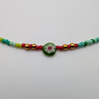 Close-up of green millefiori flower bead and gold-tone accents on multicolour choker