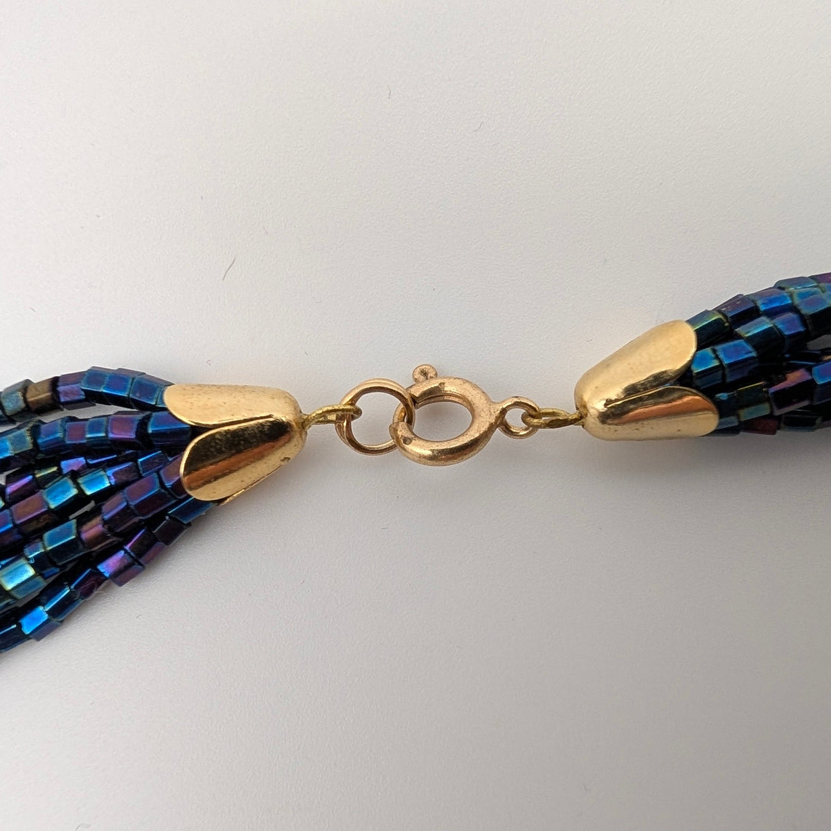 Close-up of gold-tone spring-ring clasp and end caps showing surface wear