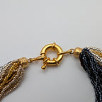 Close-up of oversized gold-tone spring-ring clasp and textured end caps
