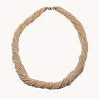 A multi-strand twisted rope necklace made of small cream-colored beads, featuring a gold clasp at the top, displayed on a neutral light gray background.